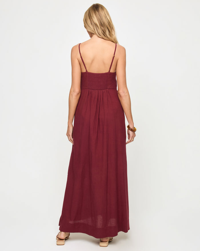 Back view of a model wearing the LSPACE Mabel Maxi Dress in sangria, featuring thin spaghetti straps, an open back with gathered waist detail, and a flowing full-length silhouette.