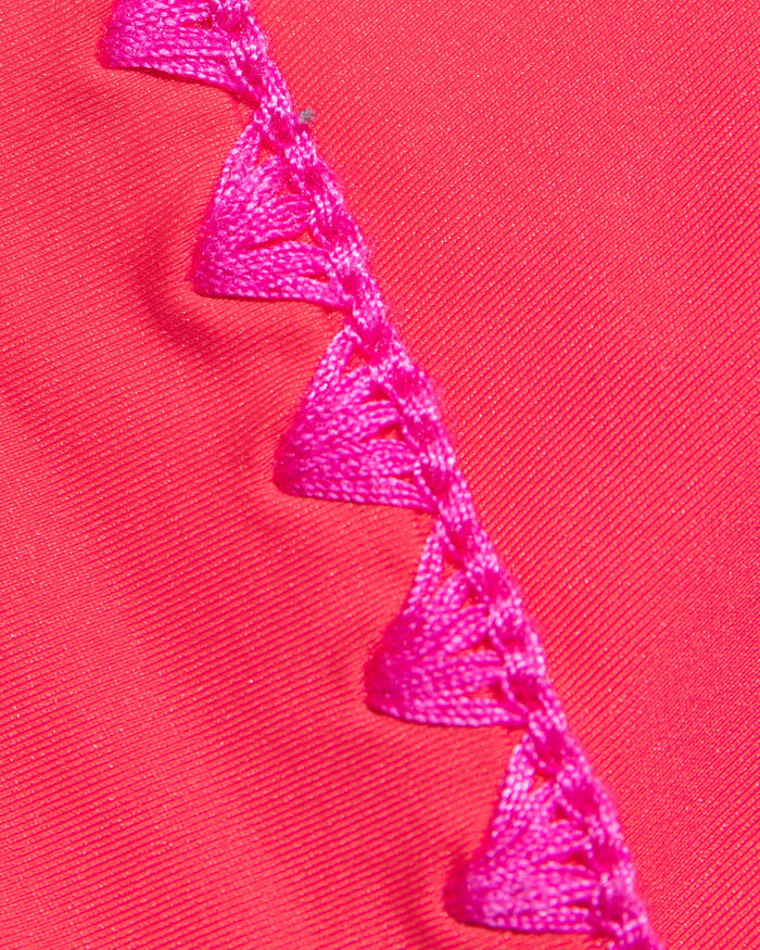 Close-up of pout coral fabric with fuchsia crochet trim detail used in the LSPACE pout-fuchsia Nadia One Piece Swimsuit.