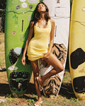 Limoncello Stripe | Badge:New Arrival_#B2AC88_#ffffff'
LSPACE Samantha Dress in limoncello stripe, lifestyle front view on model leaning against surfboards.