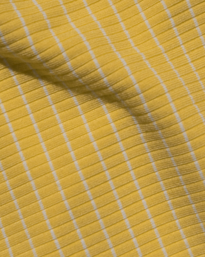 A close-up of a yellow ribbed fabric with thin white stripes.