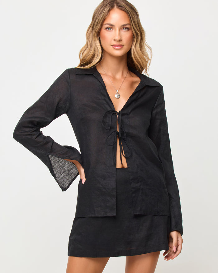 Back view of model wearing the LSPACE Venice Shirt in black, an oversized button-front shirt styled with the Venice Skort.